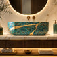 A luxury bathroom vanity setup featuring a round backlit mirror, a turquoise and gold marbled vessel sink, a white marble countertop, and a floating wood-and-matte vanity cabinet in a high-end spa-like interior.