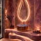 Luxury bathroom vanity featuring a wavy carved stone countertop, a ribbed round vessel sink, and a large leaf-shaped backlit mirror set against a warm brown marble wall.