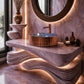 A luxurious bathroom vanity featuring a sculptural wavy stone countertop and matching stone wall and floor, with a copper-toned vessel sink, round mirror, and decorative accessories.