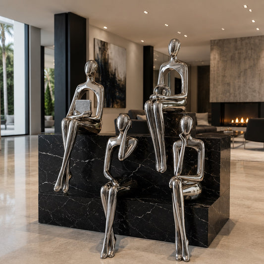 Set of silver abstract sculptures on a black marble base in a modern interior setting.