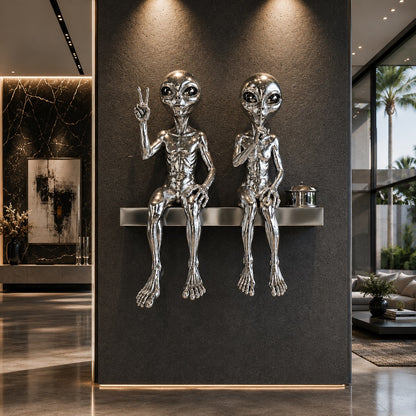 Metallic alien sculptures on a shelf against a dark wall in a modern interior setting.