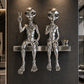 Metallic alien sculptures on a shelf against a dark wall in a modern interior setting.
