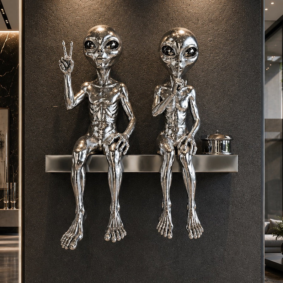 Metallic alien sculptures on a shelf against a dark wall in a modern interior setting.