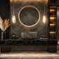 Luxury modern bathroom vanity featuring a round backlit mirror, a textured stone vessel sink, a black marble countertop with gold veins, and warm ambient lighting.