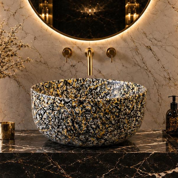 Luxury bathroom vanity featuring a round backlit mirror, a speckled gold and black vessel sink, and dark marble surfaces with gold accents.