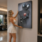 Woman admiring a modern wall sculpture of two abstract figures holding a heart in a stylish interior.