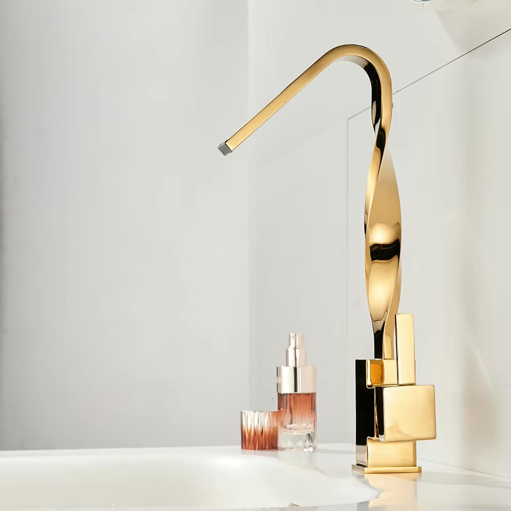 A modern high-arc gold faucet with a polished chrome base, shown installed on a white sink with cosmetic bottles in the background.