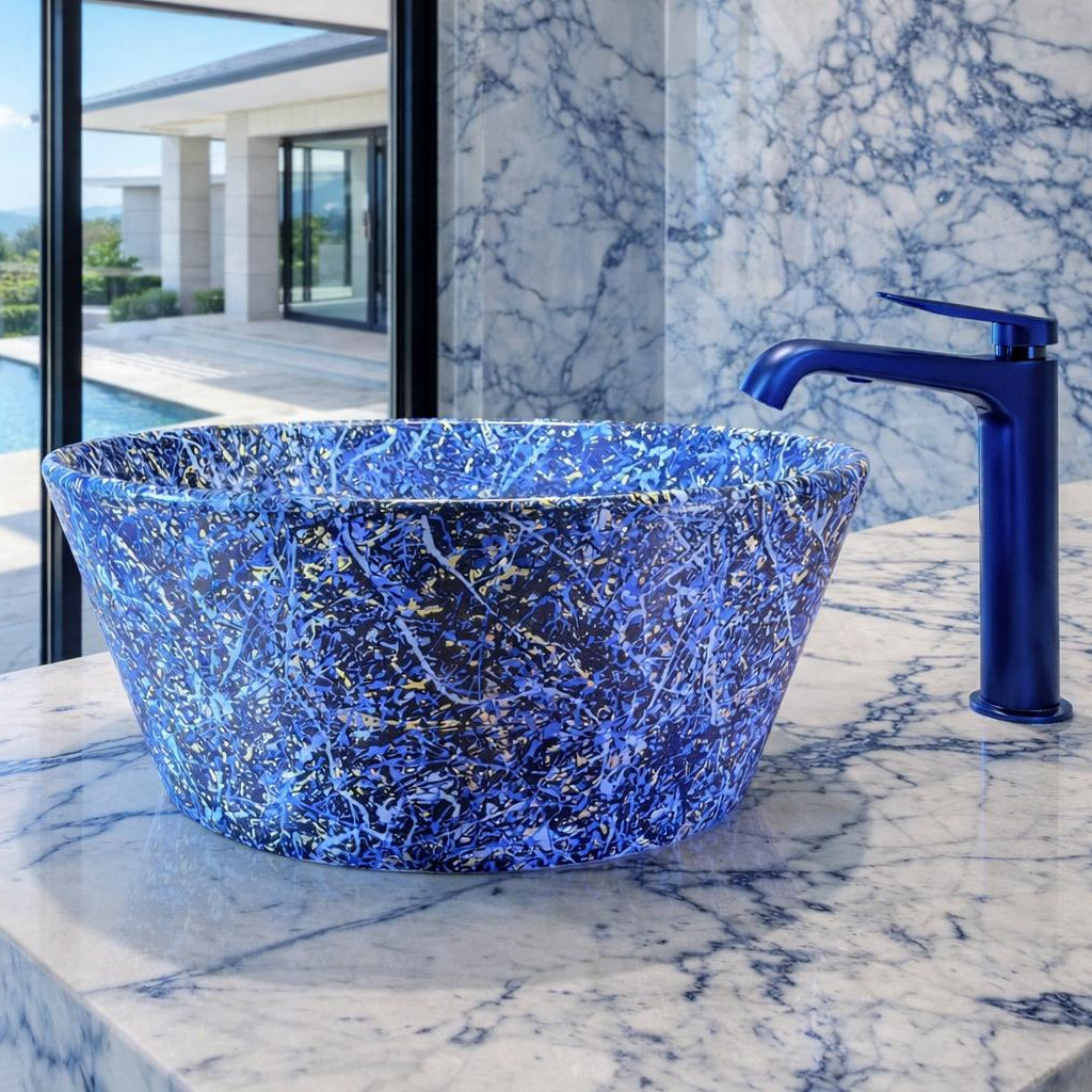 A blue marbled ceramic vessel sink with a matching blue faucet, set on a white and blue marble countertop with a pool and outdoor landscape visible in the background.